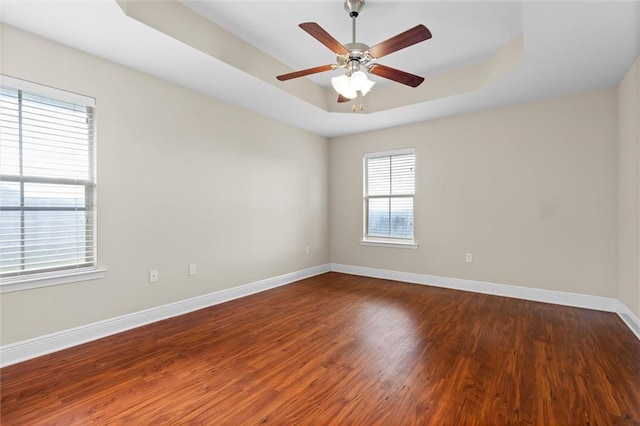 spare room featuring a tray ceiling, ceiling fan, and dark hardwood / wood-style flooring