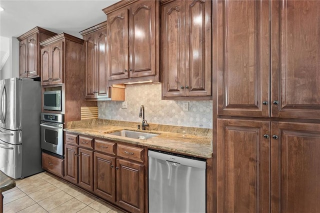 218 Ferry Ave, Saraland, AL 36571 - kitchen featuring appliances with stainless steel finishes, a sink, light tile patterned floors, decorative backsplash, and light stone counters