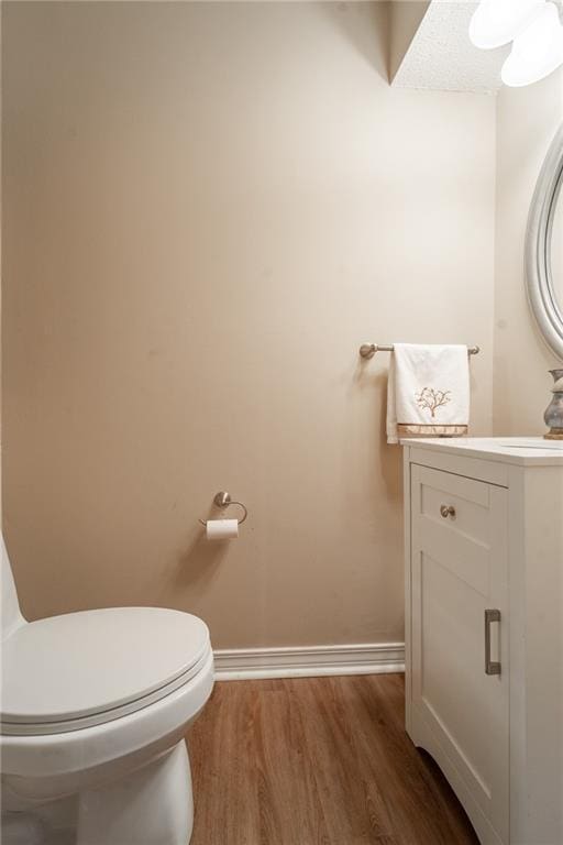 bathroom with toilet, vanity, and wood-type flooring