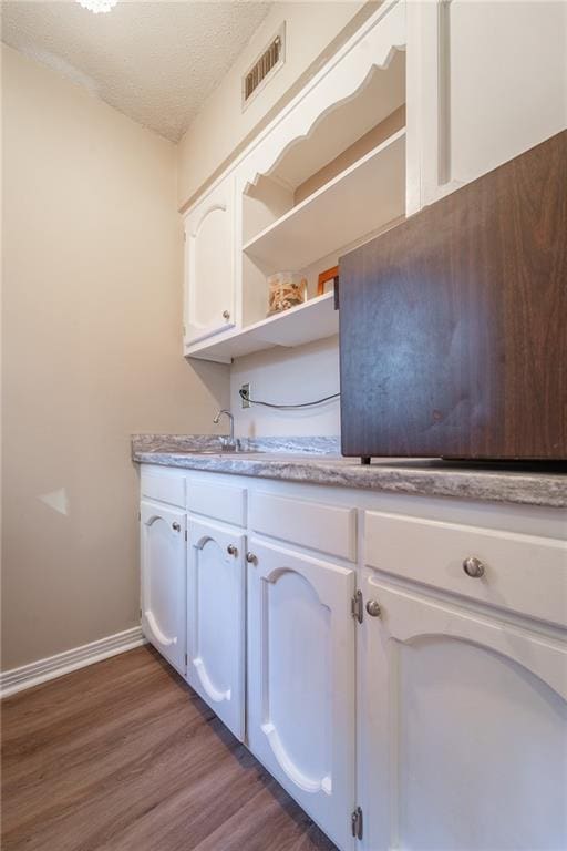 interior space with white cabinets, dark wood-type flooring, sink, and a textured ceiling