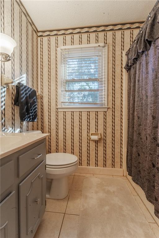 bathroom featuring toilet, vanity, tile patterned floors, and a textured ceiling