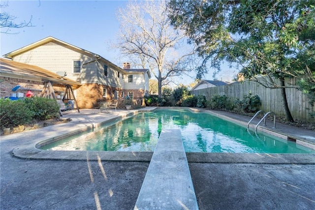 view of pool with a patio area and a diving board