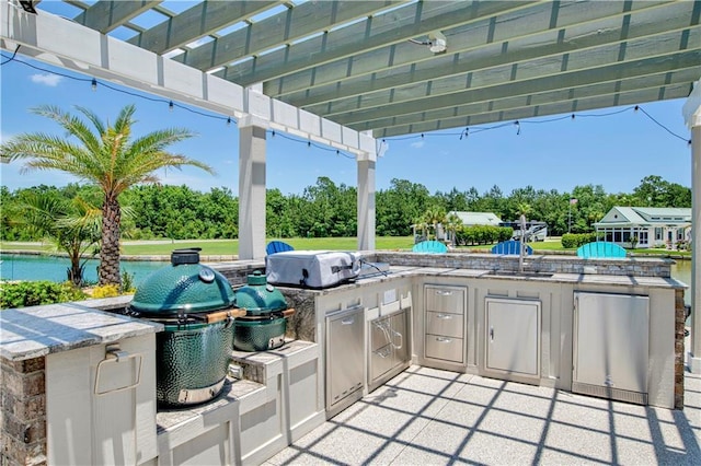 view of patio / terrace with sink, exterior kitchen, grilling area, a pergola, and a water view