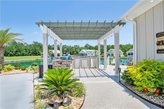 view of patio with a water view, an outdoor kitchen, and a pergola