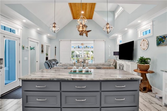 kitchen with light stone counters, decorative light fixtures, gray cabinets, and a center island