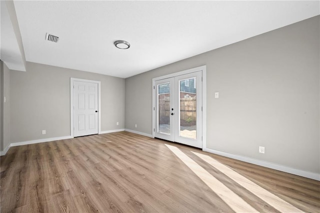 spare room featuring french doors and light wood-type flooring