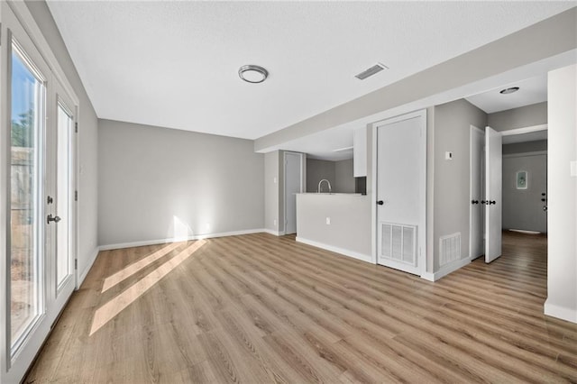 unfurnished living room featuring light hardwood / wood-style floors and sink