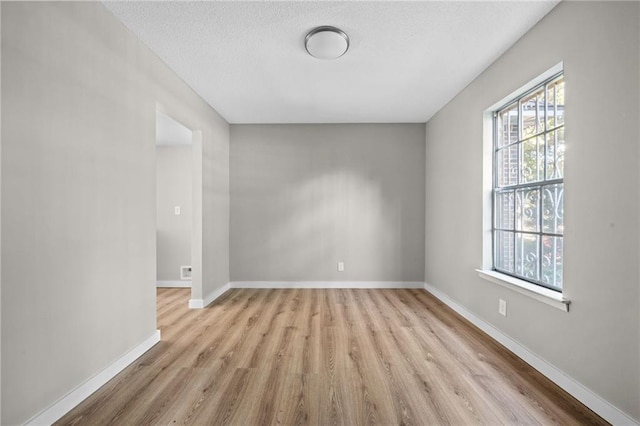 unfurnished room with light hardwood / wood-style flooring and a textured ceiling