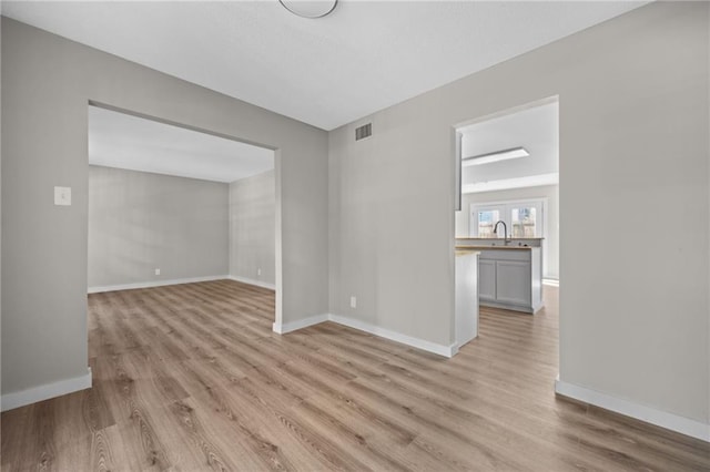 spare room with light hardwood / wood-style floors and sink