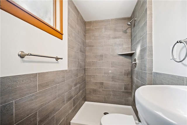 bathroom with a tile shower and toilet