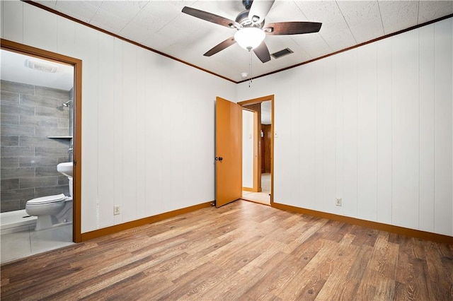 unfurnished room with ceiling fan, tile walls, ornamental molding, wood walls, and light hardwood / wood-style floors