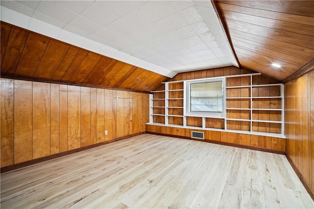 additional living space with light wood-type flooring, built in features, wooden ceiling, vaulted ceiling, and wooden walls