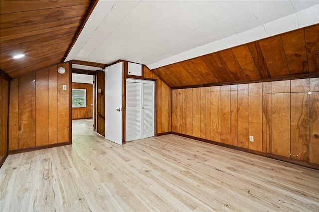 additional living space featuring wooden ceiling, vaulted ceiling, light hardwood / wood-style floors, and wood walls