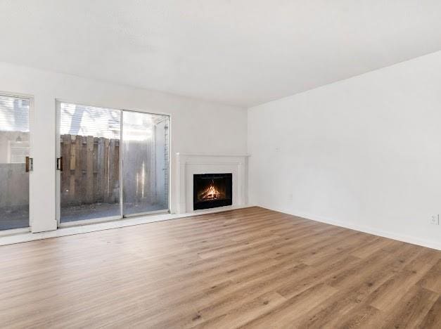 unfurnished living room with a lit fireplace and wood finished floors