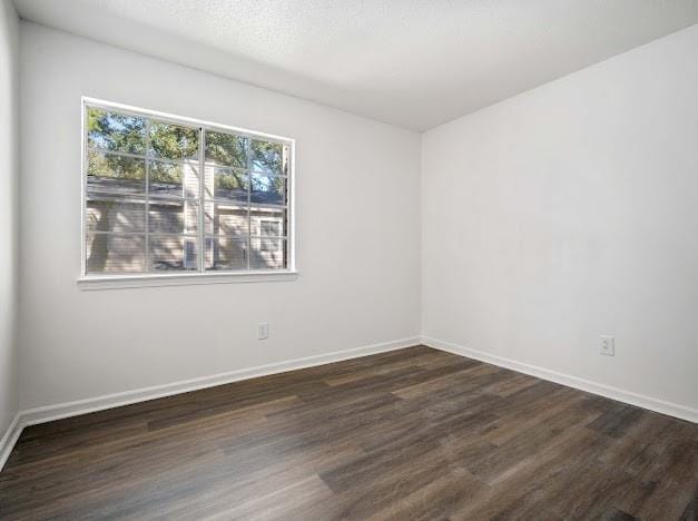 unfurnished room featuring baseboards and dark wood finished floors