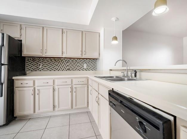 kitchen featuring light tile patterned floors, light countertops, backsplash, appliances with stainless steel finishes, and a sink