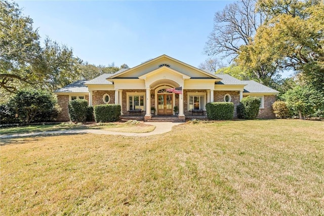 neoclassical / greek revival house with brick siding, french doors, and a front yard