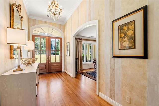 foyer featuring wood finished floors, french doors, arched walkways, crown molding, and baseboards