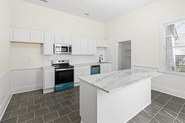 1012 Texas St, Mobile, AL 36604 - kitchen with white cabinetry, a wainscoted wall, light stone countertops, and stainless steel appliances
