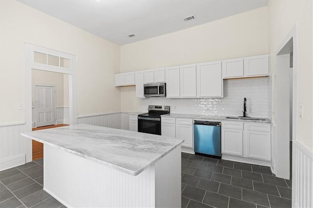 1012 Texas St, Mobile, AL 36604 - kitchen with a wainscoted wall, white cabinets, a sink, and stainless steel appliances