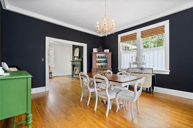 264 Mcdonald Ave, Mobile, AL 36604 - dining space featuring a chandelier, light wood-style floors, a fireplace with flush hearth, and ornamental molding
