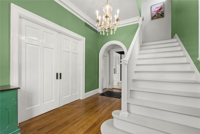 264 Mcdonald Ave, Mobile, AL 36604 - staircase featuring wood finished floors, arched walkways, a chandelier, and crown molding
