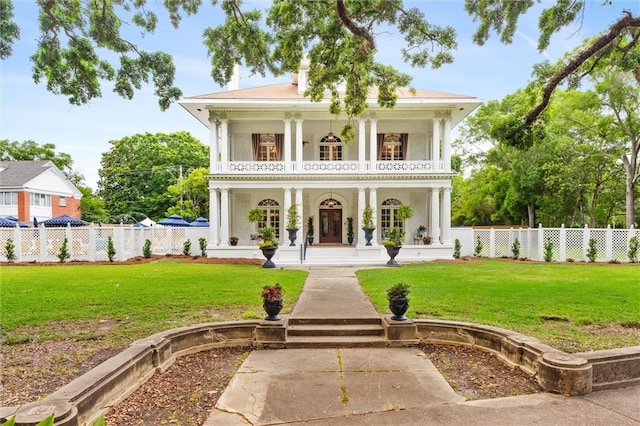 greek revival inspired property featuring a front lawn, a balcony, and a porch