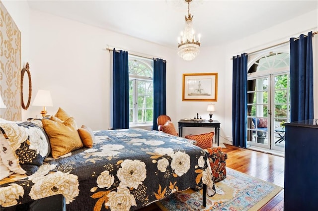 bedroom featuring an inviting chandelier, hardwood / wood-style flooring, and access to outside