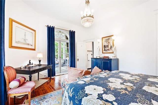 bedroom with wood-type flooring, an inviting chandelier, and access to exterior