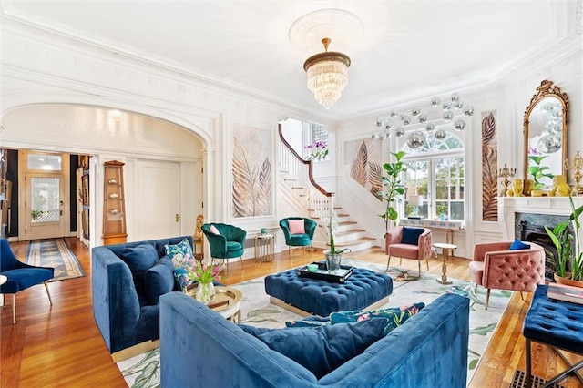 living room featuring a notable chandelier, hardwood / wood-style floors, a fireplace, and ornamental molding