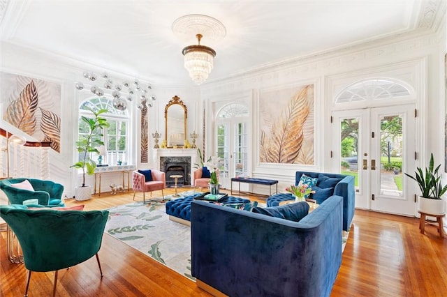 living room with a notable chandelier, wood-type flooring, french doors, and crown molding