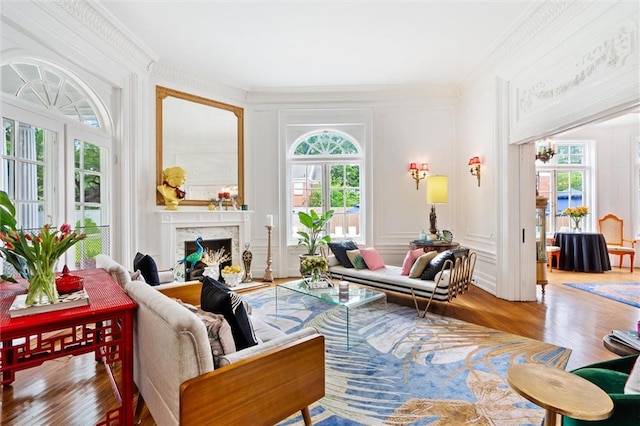 living room featuring a high end fireplace, ornamental molding, hardwood / wood-style flooring, and a wealth of natural light