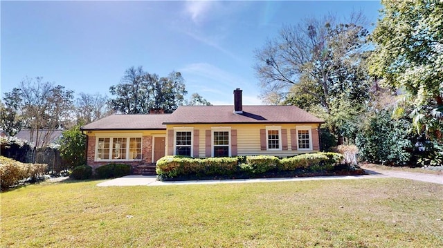 ranch-style house featuring brick siding, a chimney, and a front yard