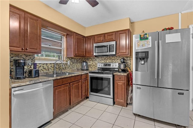 kitchen featuring light stone countertops, sink, stainless steel appliances, backsplash, and light tile patterned floors