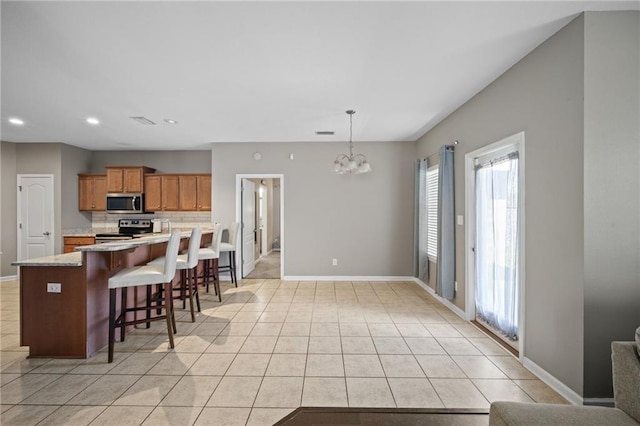 kitchen with hanging light fixtures, an inviting chandelier, a breakfast bar area, light tile patterned floors, and appliances with stainless steel finishes