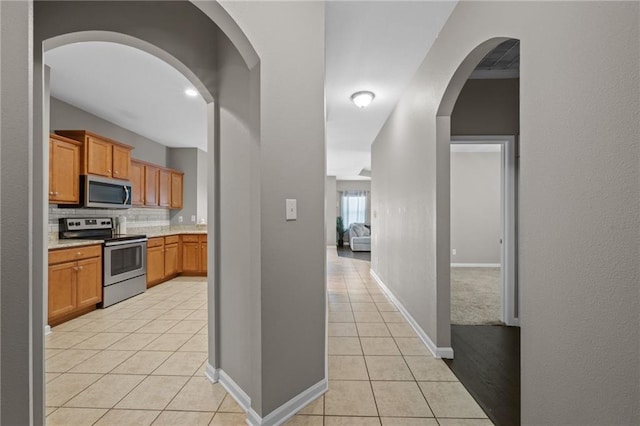 kitchen with backsplash, light tile patterned flooring, and appliances with stainless steel finishes