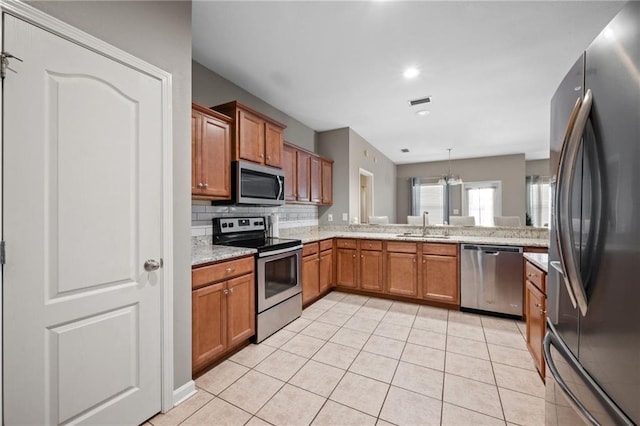 kitchen with sink, stainless steel appliances, backsplash, decorative light fixtures, and light tile patterned floors