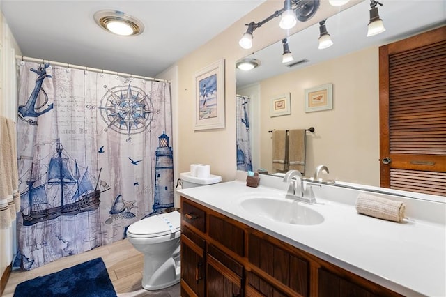 bathroom featuring toilet, visible vents, wood finished floors, and vanity