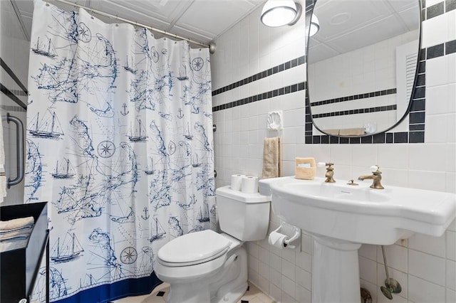 bathroom with toilet, curtained shower, and tile walls