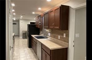 kitchen featuring black refrigerator, sink, tasteful backsplash, light tile patterned floors, and stainless steel dishwasher