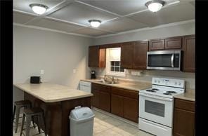 kitchen featuring kitchen peninsula, white electric range, and a breakfast bar