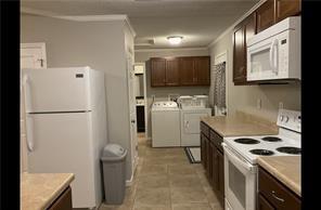 kitchen featuring light tile patterned floors, ornamental molding, dark brown cabinets, washing machine and dryer, and white appliances