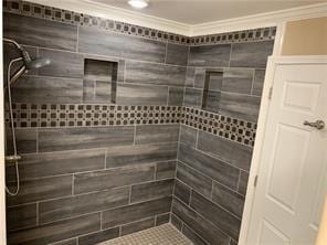 bathroom featuring tiled shower and crown molding