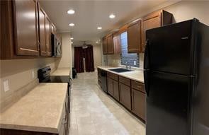 kitchen featuring black fridge, sink, and stove