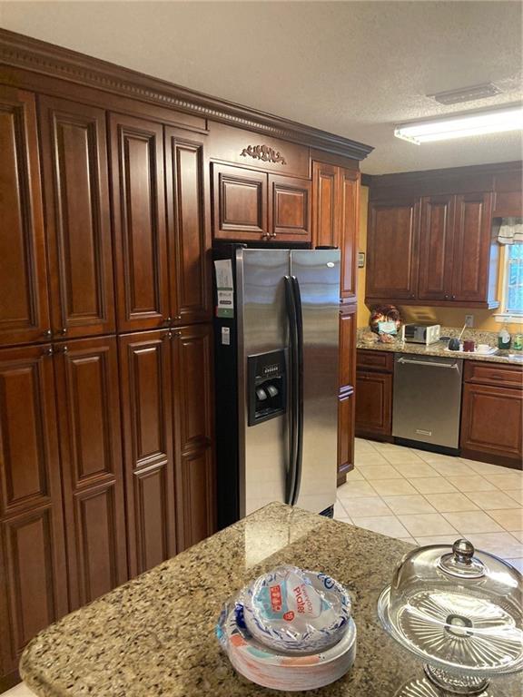 724 Mae St, Saraland, AL 36571 - kitchen with appliances with stainless steel finishes, light tile patterned floors, and light stone counters