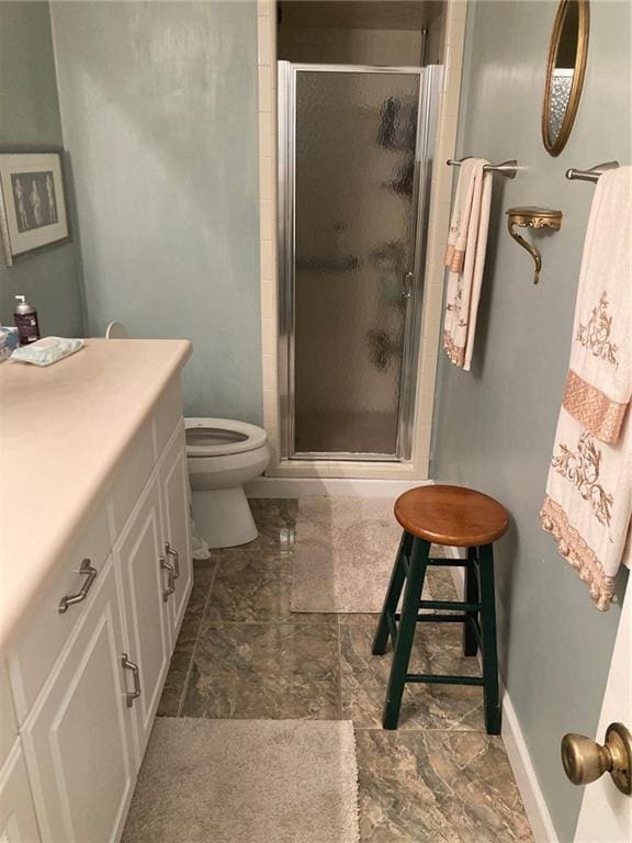 bathroom featuring vanity, toilet, and a shower with door