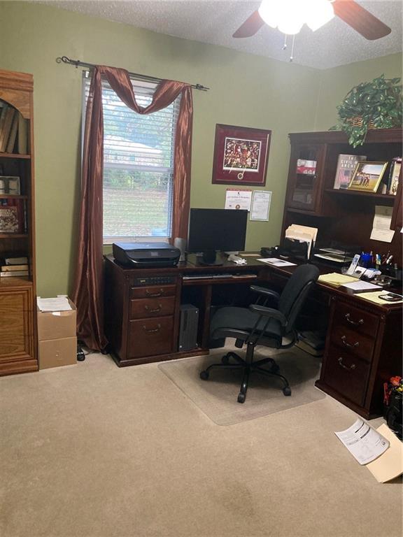 carpeted office with a textured ceiling and ceiling fan