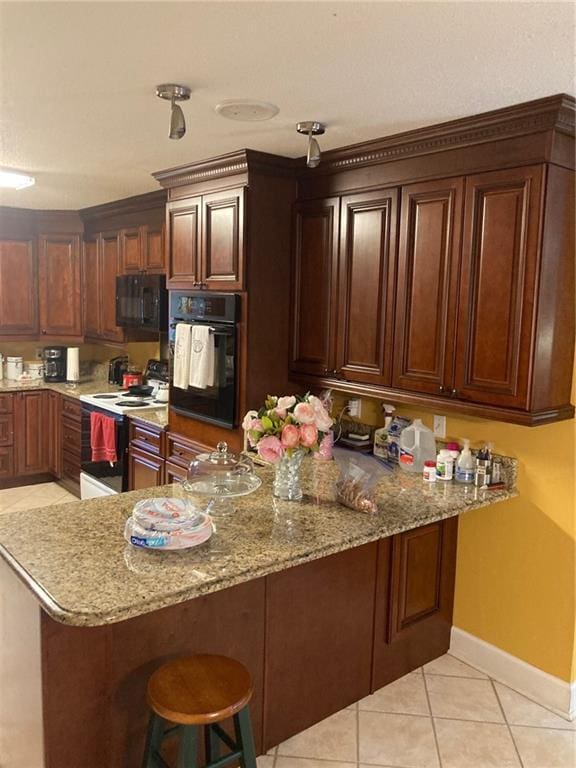 724 Mae St, Saraland, AL 36571 - kitchen with black appliances, a breakfast bar, a peninsula, light tile patterned flooring, and light stone countertops