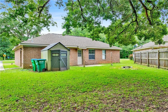 rear view of property featuring a lawn and a storage unit