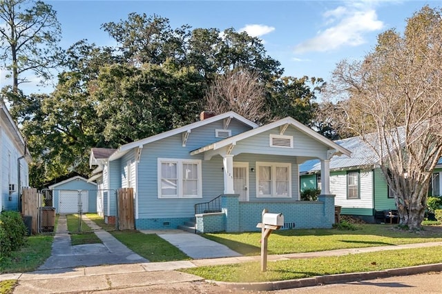 bungalow-style house with a front yard, a garage, an outdoor structure, and covered porch